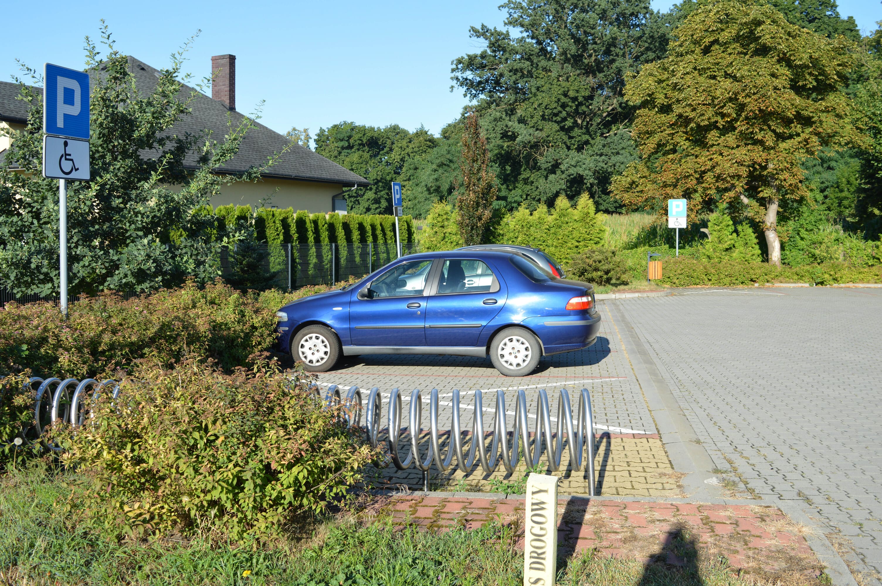 Brukowane kostką, oznaczone znakiem parking miejsce parkingowe dla osób z niepełnosprawnościami.